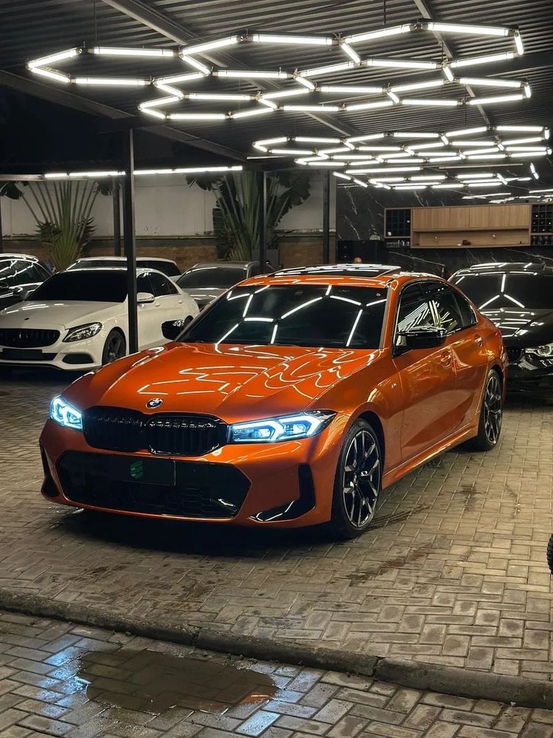 BMW 320i com envelopamento laranja, vista dianteira em três quartos
